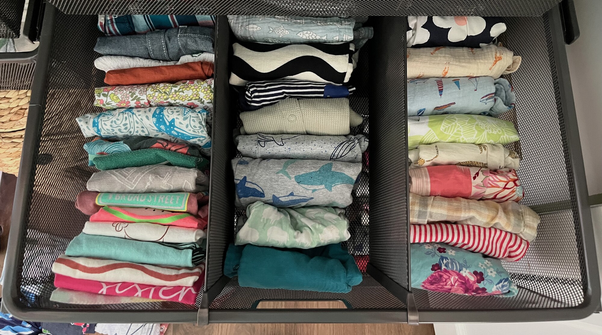 Kids' clothes folded into a labeled mesh drawer